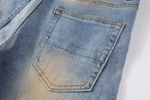 Macro detail of vintage washed denim jeans showing back pocket with contrast stitching