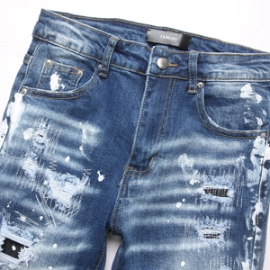 Blue high street skinny jeans with distressed ripped detailing and white paint splashes
