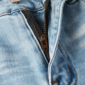 Detailed close-up of premium blue washed denim fabric featuring a bronze YKK metal zipper