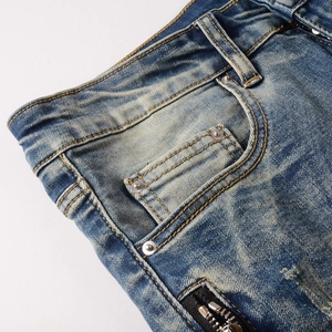 Macro detail of blue distressed jeans with silver rivets and decorative black zipper