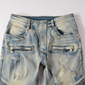 Detailed view of distressed light blue biker jeans with knee pleats and zipper pockets