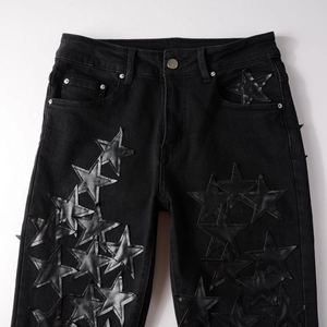 Close-up of black denim jeans featuring star leather patches and detailed stitching