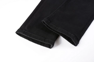 Detailed close-up of double-stitched hem and fabric texture on black denim jeans