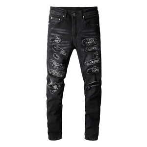 Men's black slim fit jeans featuring heavy distressed patches and reflective sequins