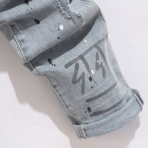Slim fit light blue distressed jeans with paint splatter and graffiti graphic prints