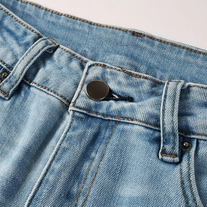 Detail of waist stitching, metal button, and belt loops on light blue denim jeans