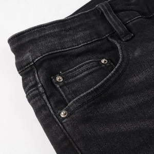 Detail view of denim jeans featuring waist band, pocket, and metallic rivet studs decoration