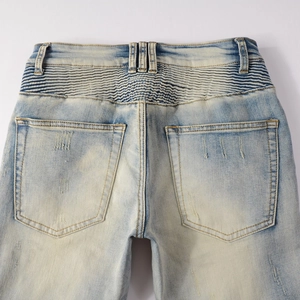 Close-up of distressed light blue biker jeans showing ribbed back panel and worn pockets