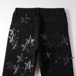 Detail of black leather star patches and fine stitching on the back of denim jeans