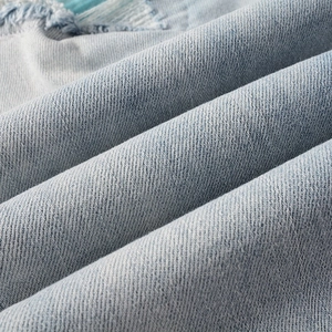 Macro detail of distressed denim fabric with ripped edges and washed blue texture
