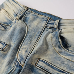 Detail of vintage distressed denim jeans featuring yellow wash effects and reinforced stitching