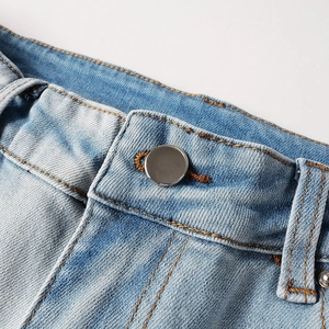 Detail of light blue washed denim waist with yellow stitching and silver metal button