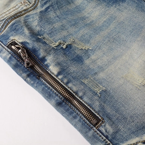 Detail of blue biker jeans featuring industrial metal zippers and vintage distressed denim