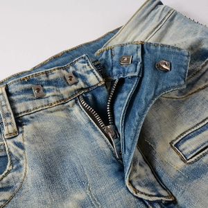Detailed macro view of vintage blue distressed denim jeans with metal hook and zipper