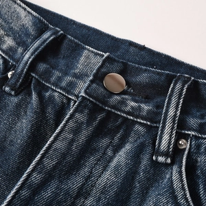 Detail of dark blue denim jeans waist with metal button and precision stitching