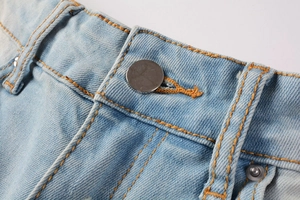 Detail of light blue denim waist with silver button and bright orange contrast stitching