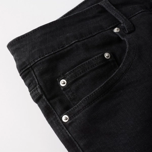 Detail of black denim side pocket with silver metal rivets and double stitching
