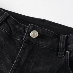 Close-up of black denim waist with silver metal button and precise stitching detail