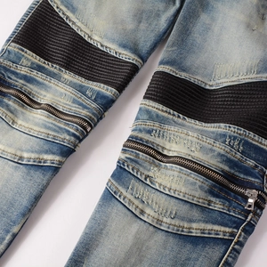 Detail of light blue biker jeans showing black ribbed panels and metal zipper accents