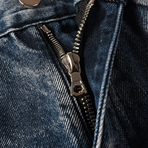Detailed macro view of high-quality silver metal zipper and button on dark blue denim jeans