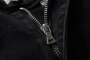 Detailed close-up of premium silver metal zipper on high-street black denim jeans
