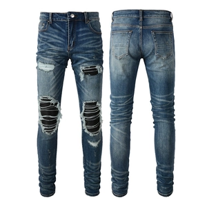 Détails d'un jean bleu délavé avec empiècements patchwork plissés noirs et déchirures