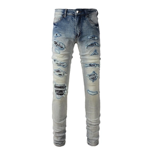 Detail of ripped light blue jeans with black and white floral pattern patches