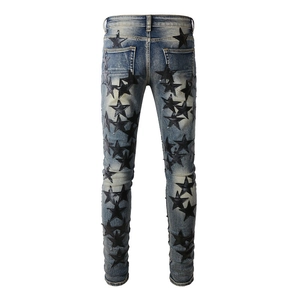 Detail of slim fit denim jeans featuring black leather star patches and washed finish