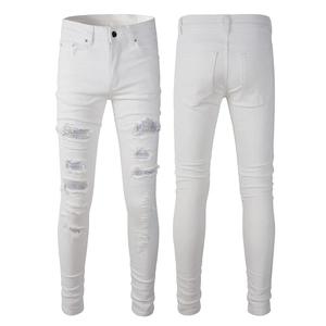 Detailed close-up of distressed white slim jeans with sparkling rhinestone patchwork accents