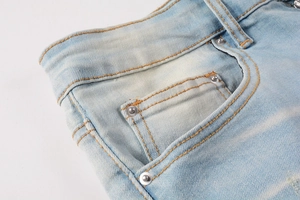 Detailed macro view of light blue denim jeans with classic orange stitching and rivets