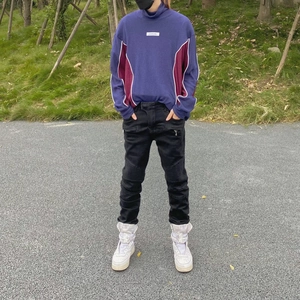 Detail view of purple patchwork high-neck knit sweater and black cargo joggers with pockets