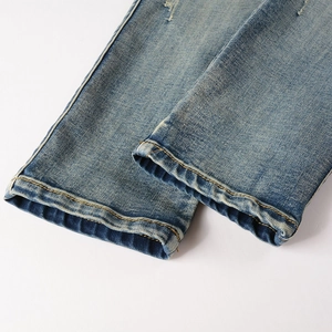 Detailed macro view of faded light blue denim jeans cuff with yellow double stitching