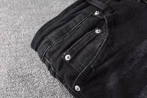 Detail of waist and pocket with metal rivets on black washed denim jeans