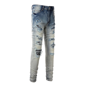 Detail view of heavy distressed denim with striped fabric patches and washed texture