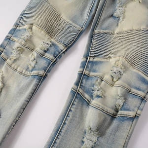 Macro detail of distressed biker jeans with ribbed panels and vintage faded wash finish