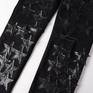 Detail of black jeans with leather star patches and distressed ripped hole street style