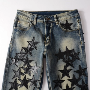 Close-up of vintage blue jeans featuring black leather star patches and retro washed denim