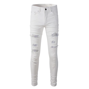 Detail view of distressed white slim jeans featuring silver sequin patches and ripped texture