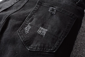 Close-up of distressed back pocket detail on black streetwear denim jeans for men
