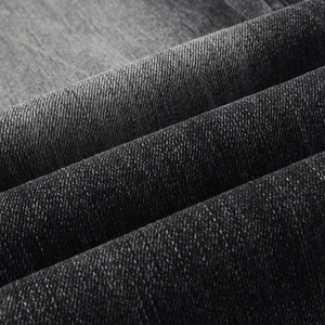 Gros plan détaillé du tissu denim gris foncé montrant la texture sergée et le fini délavé