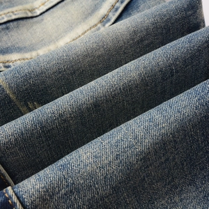 Macro detail of high-density twill denim fabric with washed blue texture and stitching
