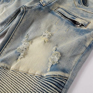 Close-up of acid wash biker jeans featuring distressed holes and pleated knee details
