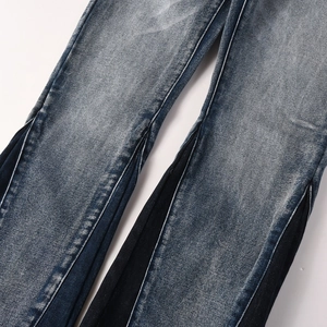 Detail of vintage washed denim jeans featuring contrast side paneling and distressed texture