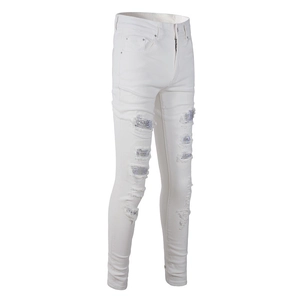 Detailed view of white slim denim with distressed holes and purple rhinestone patches