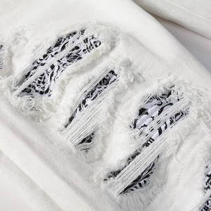 Dettaglio dei jeans slim bianchi elasticizzati con strappi e fodera con stampa paisley