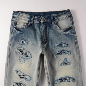 Detail of light blue washed jeans with bandana patches and ripped distressed effects