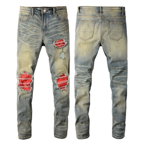 Men's slim fit distressed blue jeans featuring red bandana patchwork and ripped details