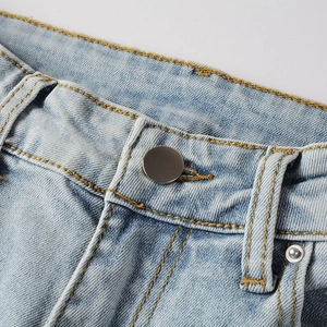 Detailed close-up of light blue denim jeans showing silver metal button and yellow stitching