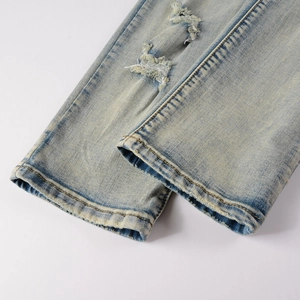 Close-up of distressed denim hem with yellow-tinted wash and worn edge detail