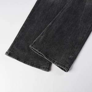 Détail du tissu denim gris foncé délavé avec ourlet à double couture sur un pantalon évasé